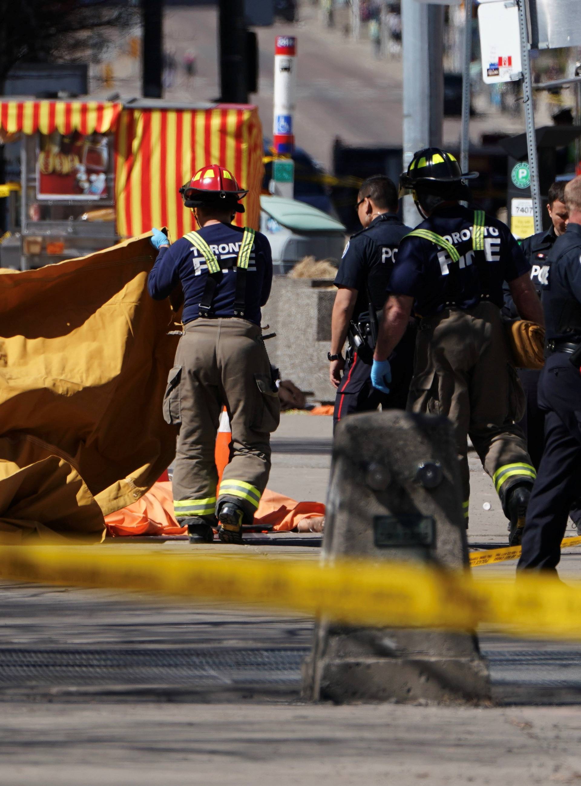 Firemen cover a victim of an incident where a van struck multiple people at a major intersection in Toronto's northern suburbs