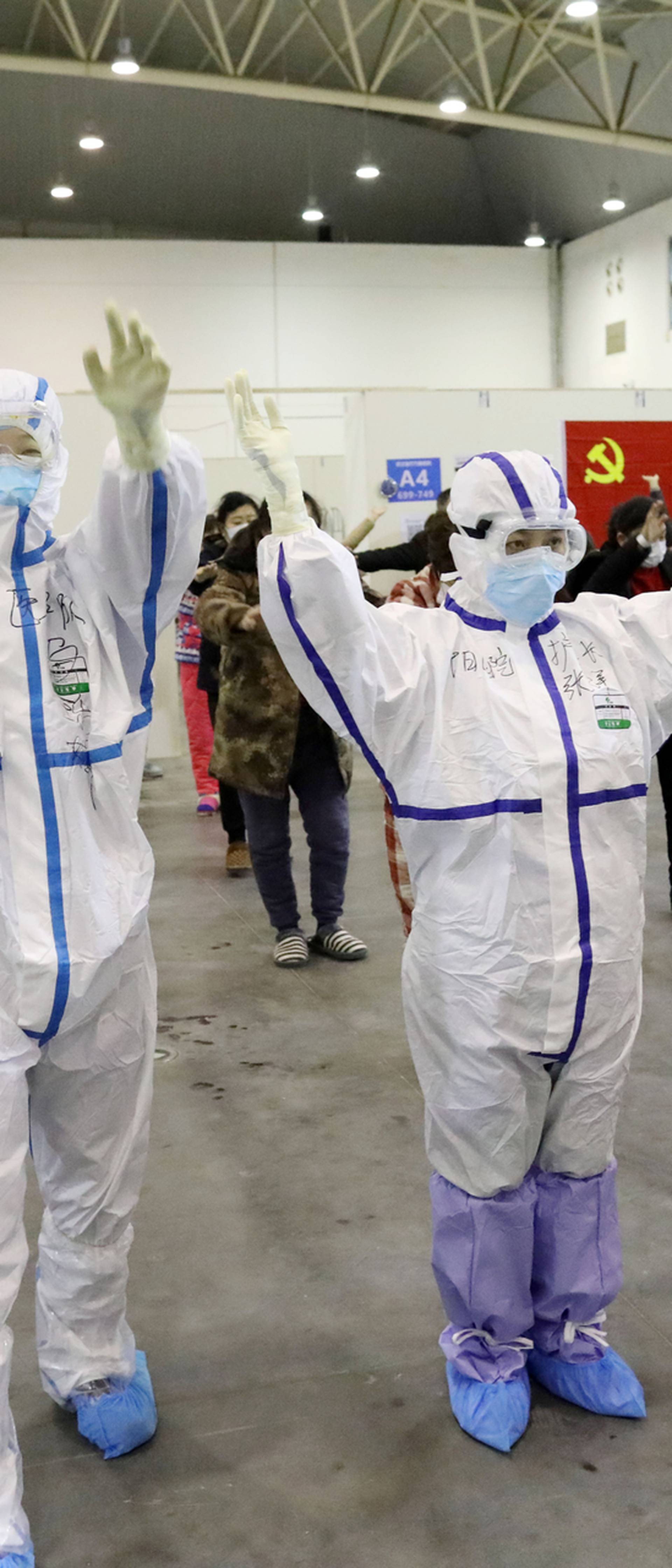 Medical workers in protective suits dance with patients inside the Wuhan Parlor Convention Center that has been converted into a makeshift hospital following an outbreak of the novel coronavirus