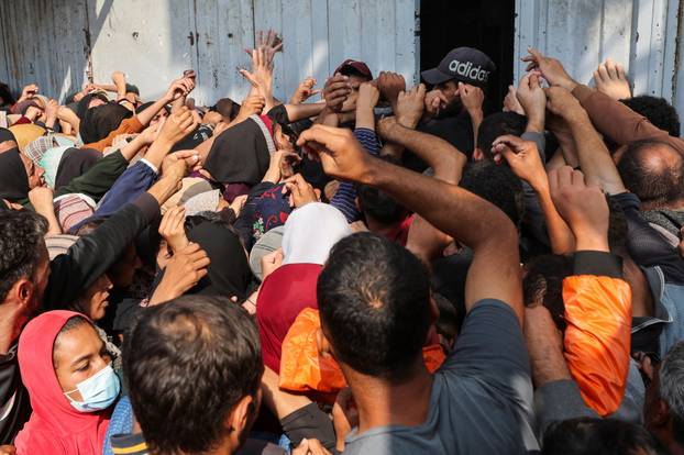 Palestinians gather as they wait to buy bread from a bakery, in Deir Al-Balah, central Gaza Strip