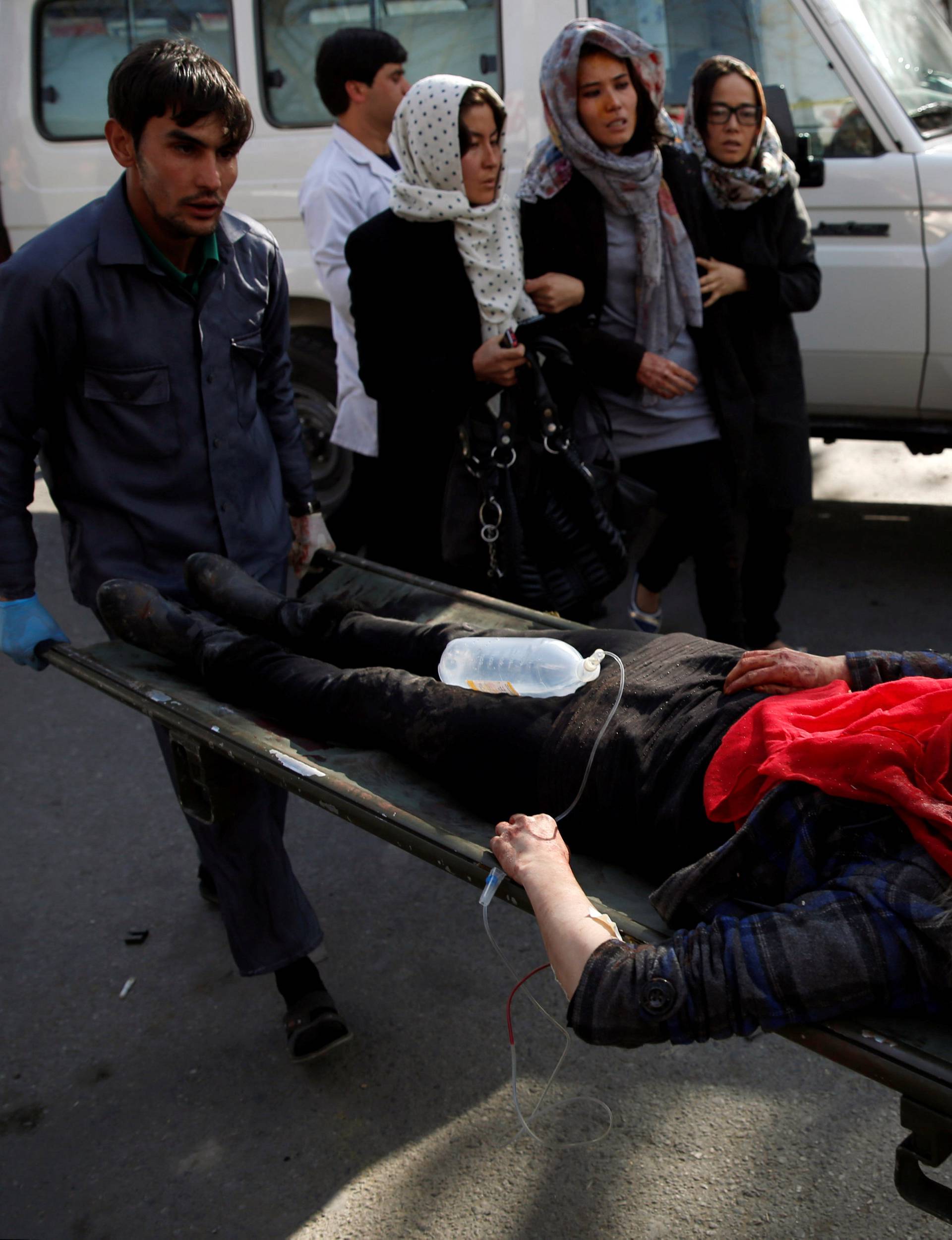 People carry injured woman to hospital after blast in Kabul