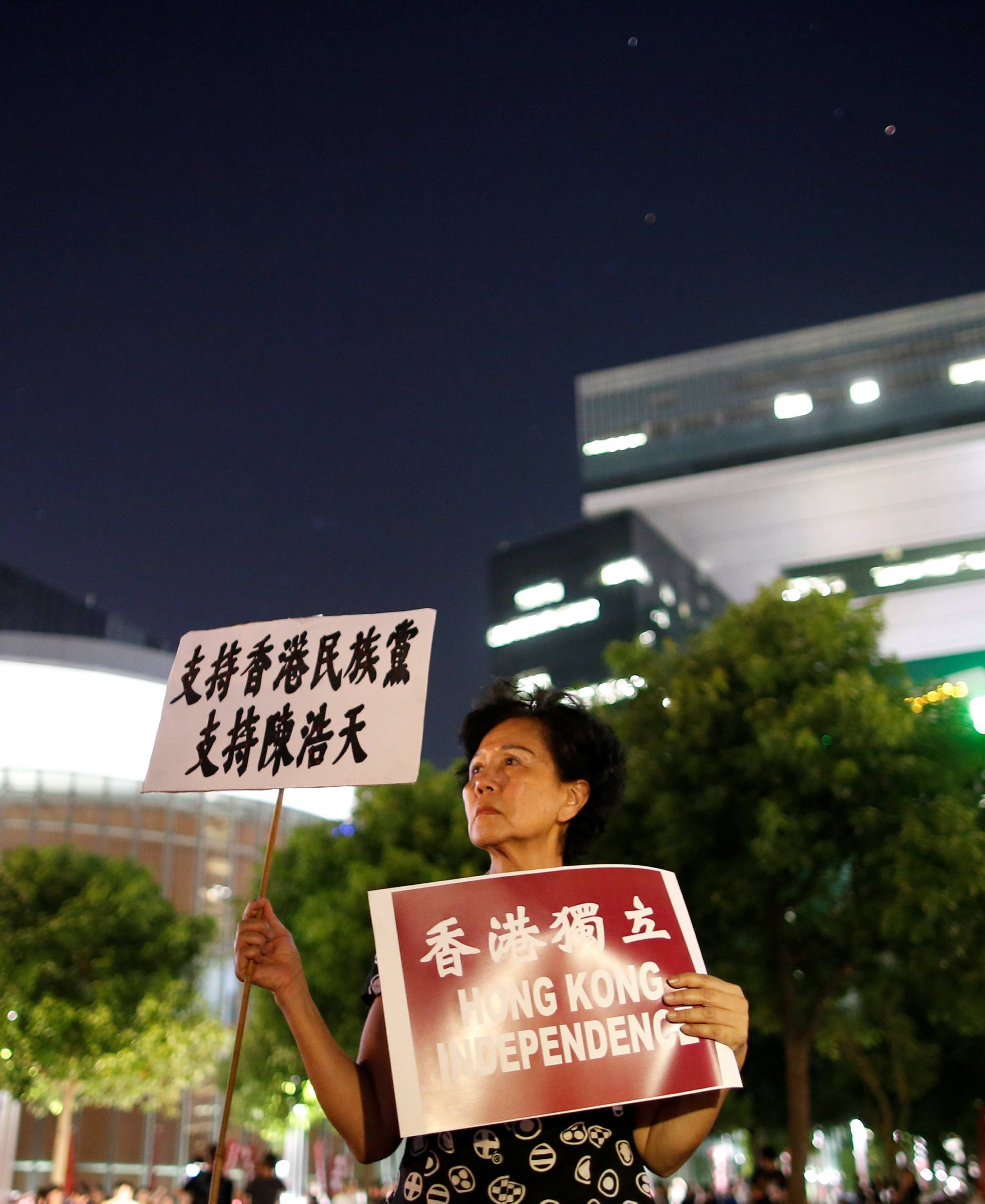 A protester holds signs during a rally in support of independence advocates who have been barred from the Legislative Council elections in Hong Kong