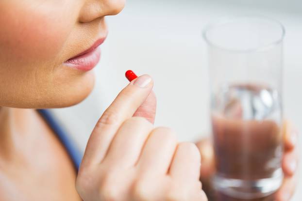 close up of woman taking medicine in pill