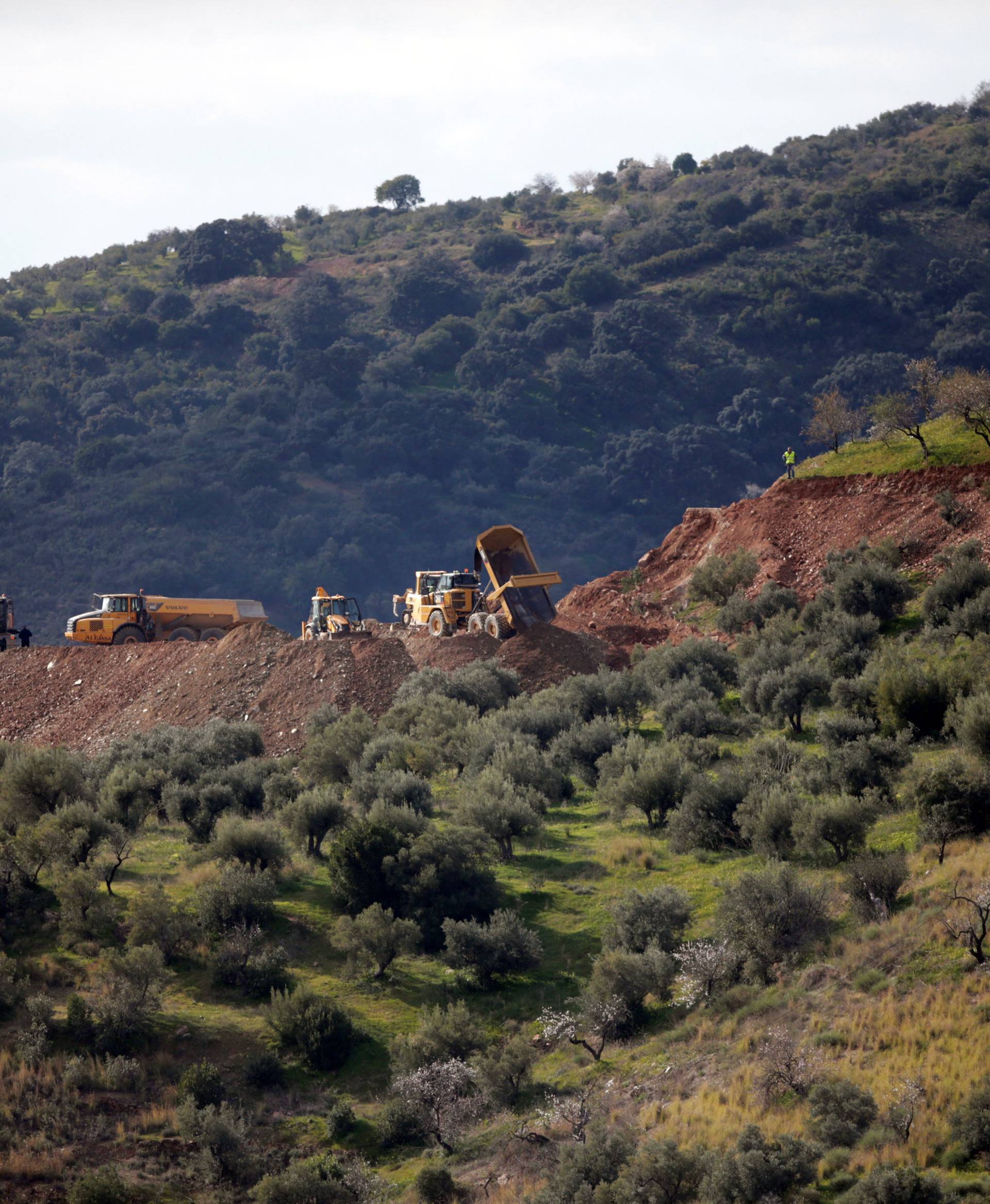 A digger and trucks remove sand in the area where Julen, a Spanish two-year-old boy fell into a  deep well when the family was taking a stroll through a private estate, in Totalan