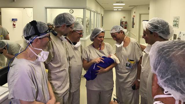 Medical team hold the first baby born via uterus transplant from a deceased donor, at the hospital in Sao Paulo