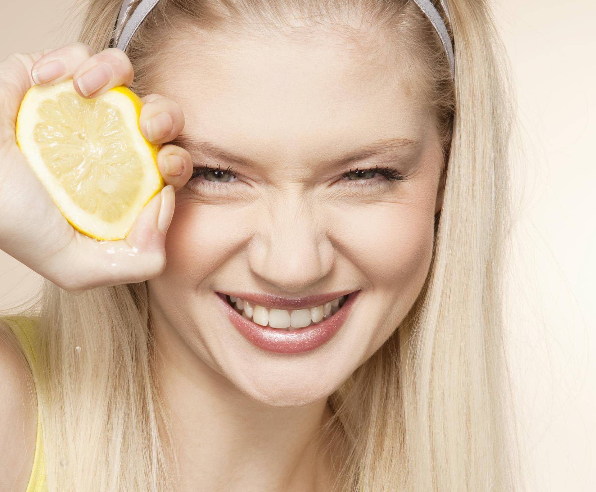 Young woman squeezing lemon, studio shot