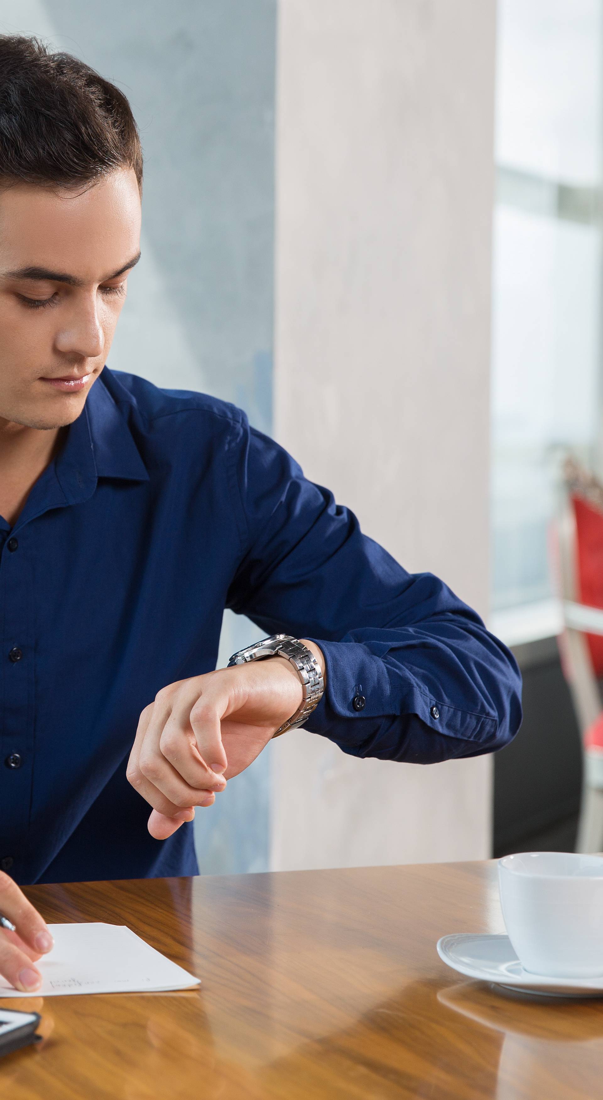 Serious Young Businessman Looking at Wrist Watch