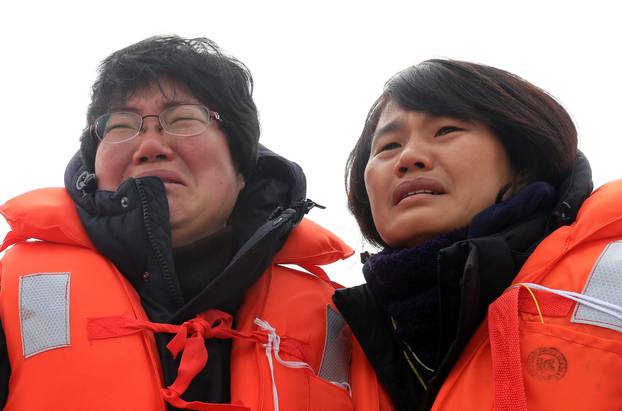 Family members of victims onboard the sunken ferry Sewol react as they look on during its salvage operations at the sea off Jindo