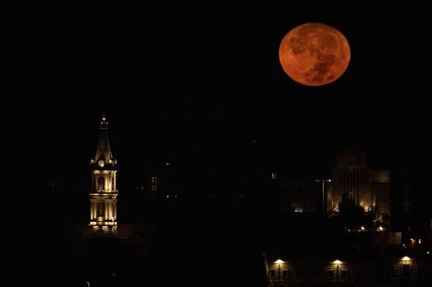 A supermoon, also known as a Blue Moon is seen above the clocktower of the Monastery of Saint Saviour in Jerusalem's Old City