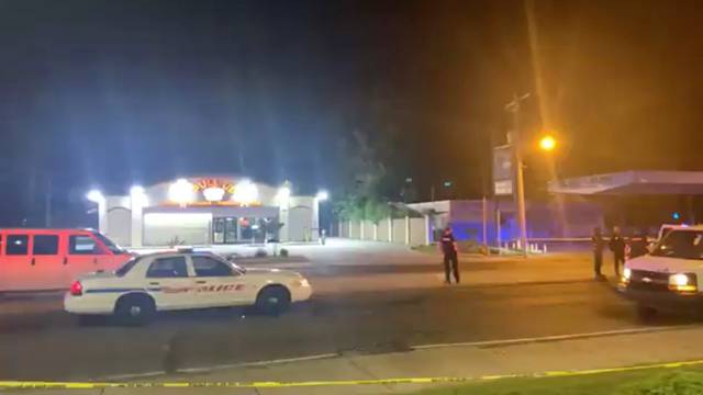Police personnel and their vehicles are seen near the scene in the aftermath of a drive-by shooting at a liquor store in Shreveport, Louisiana