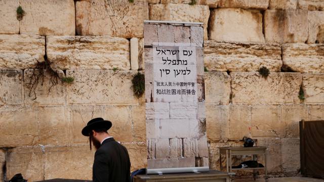 A Jewish worshipper prays next to a placard at the Western Wall in Jerusalem's Old City