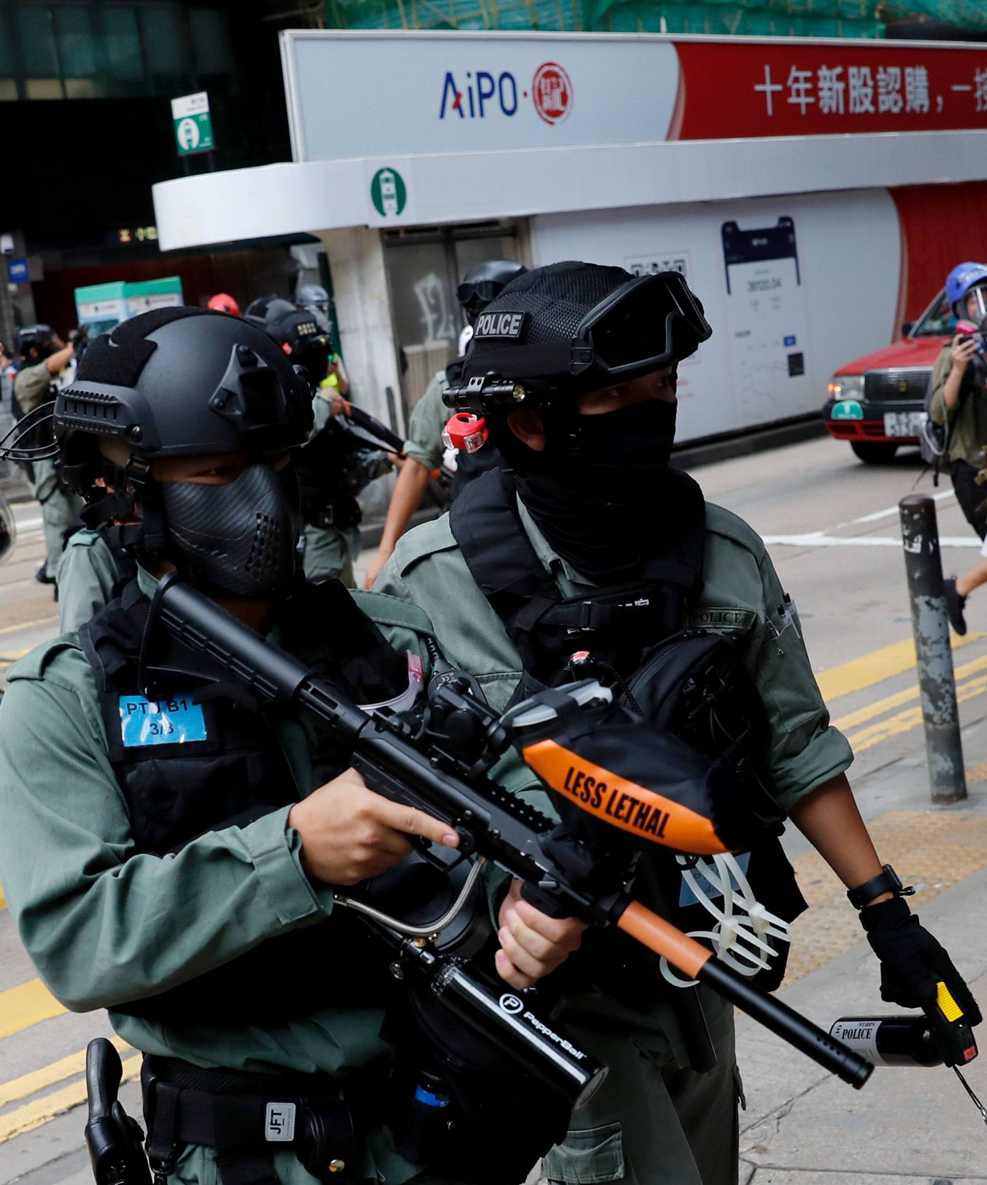 Riot police disperse anti-government demonstrators during a lunch time protest in Central, as a second reading of a controversial national anthem law takes place in Hong Kong