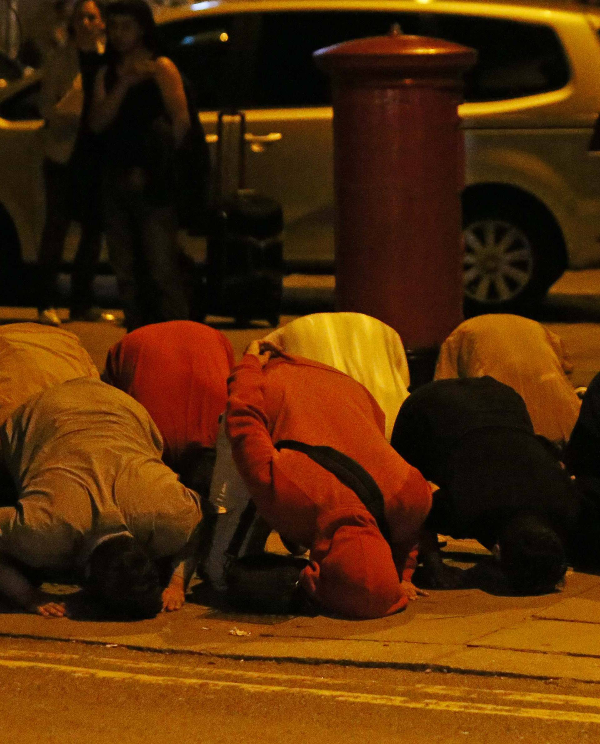 Men pray after a vehicle collided with pedestrians near a mosque in the Finsbury Park neighborhood of North London