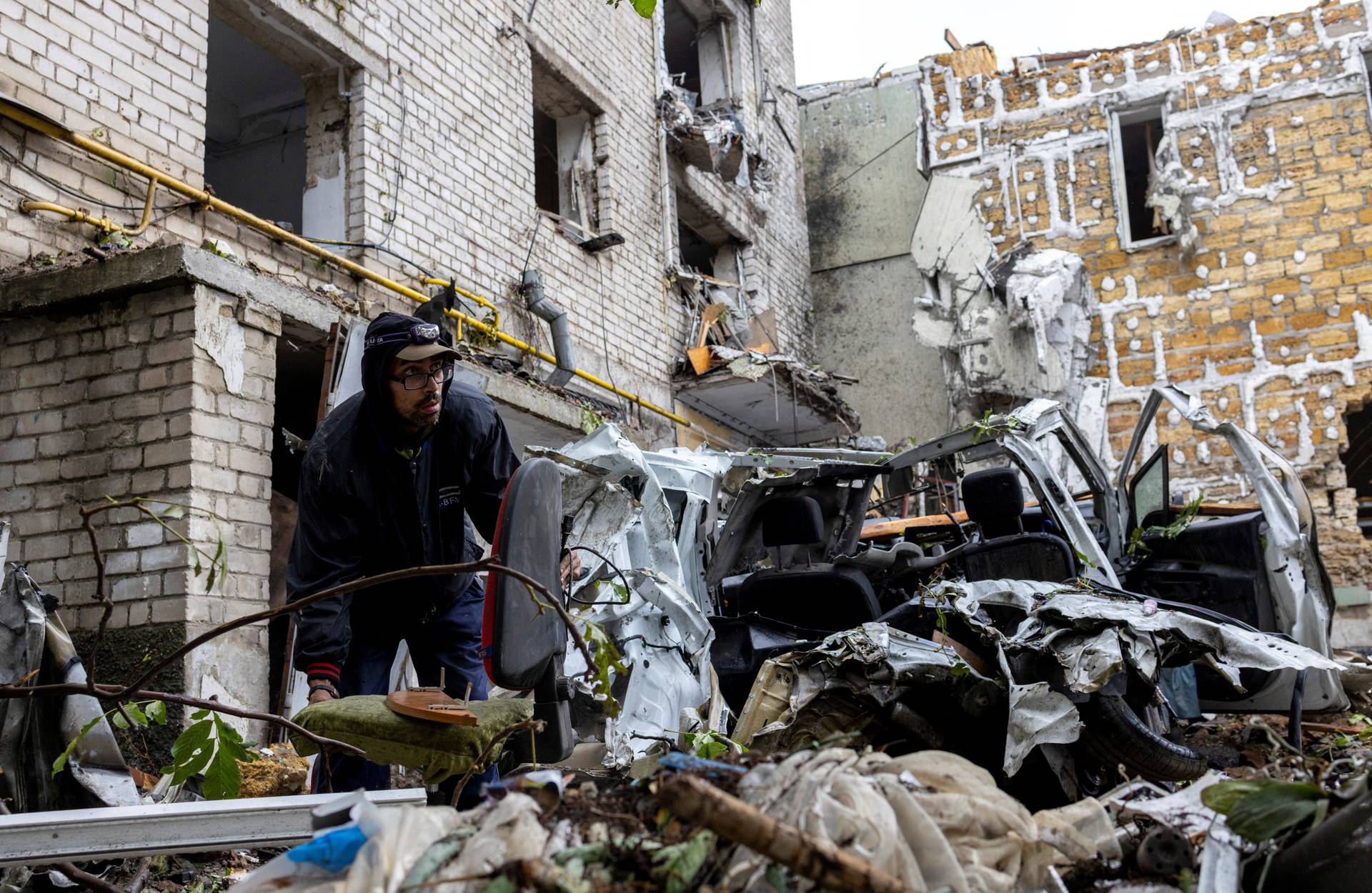 A man carries a chair away from a residential building destroyed by a strike in Mykolaiv
