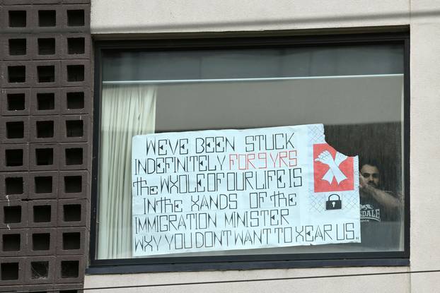 A man looks out after placing a banner in a window of the Park Hotel, believed to be holding Serbian tennis player Novak Djokovic, in Melbourne