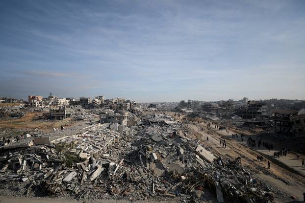 Displaced Palestinians walk past the rubble as they attempt to return to their homes, in the northern Gaza Strip