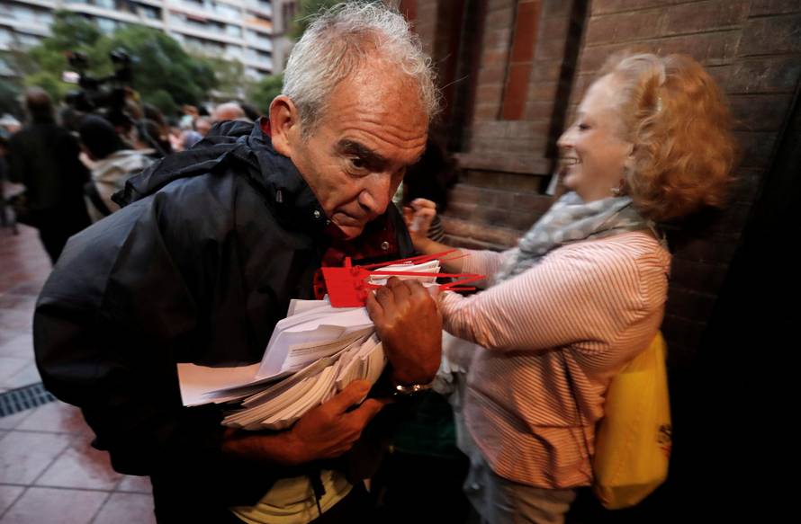 A  man holds ballots at a polling station for the banned independence referendum in Barcelona