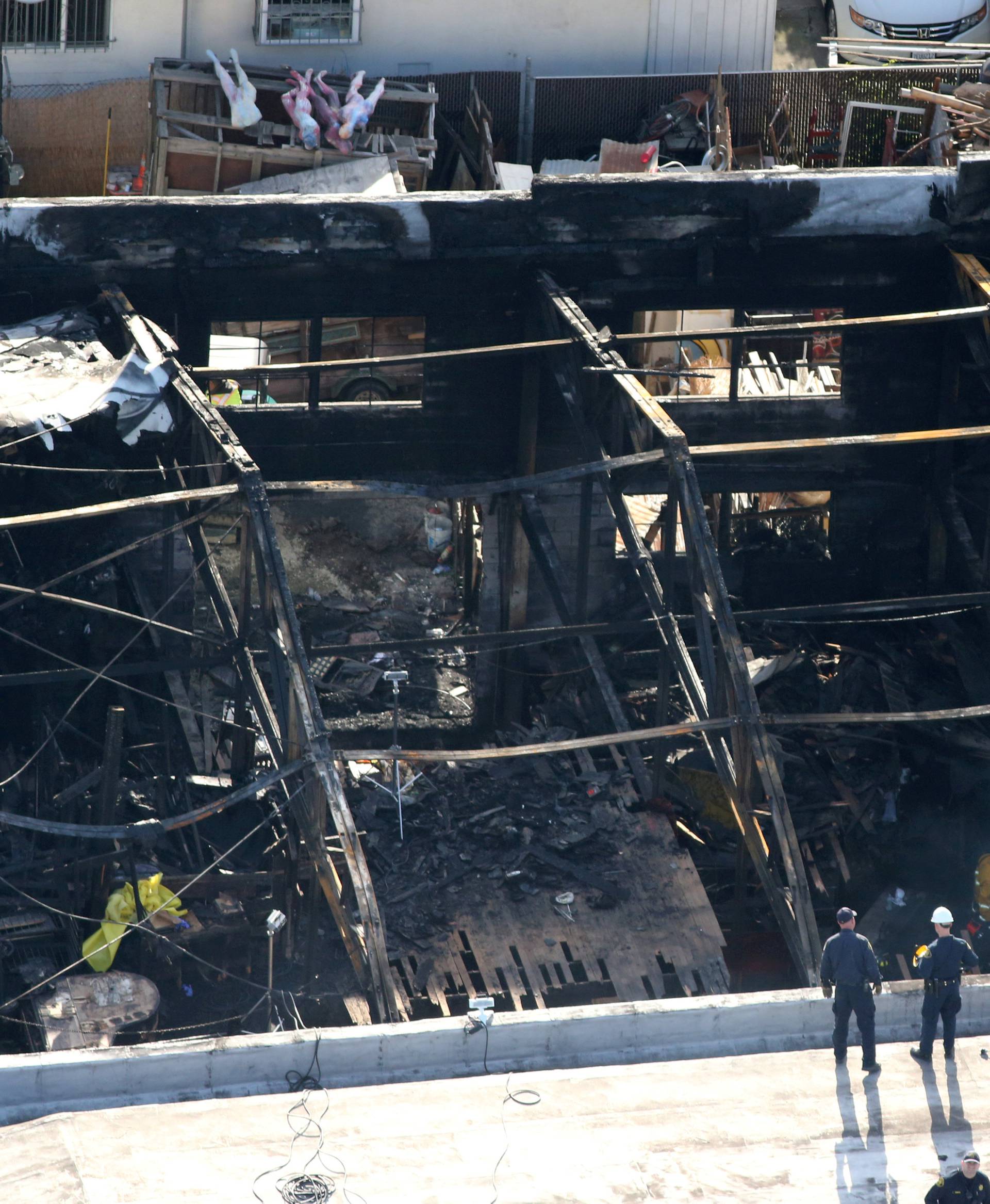 FILE PHOTO: Firefighters work inside the burned warehouse following the fatal fire in the Fruitvale district of Oakland