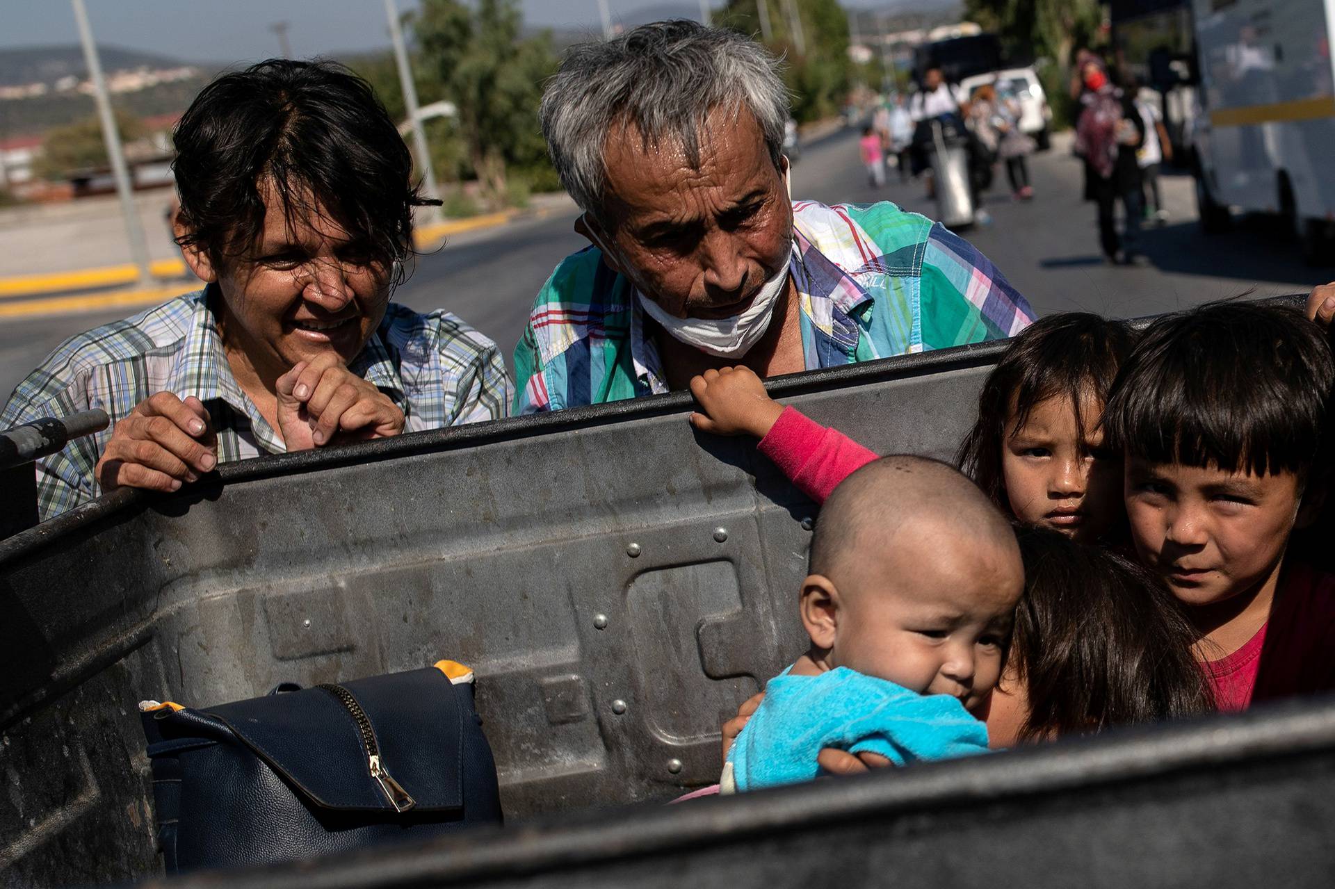 Two men push a garbage bin with their belongings as children sit inside the bin, following a fire at the Moria camp for refugees and migrants on the island of Lesbos