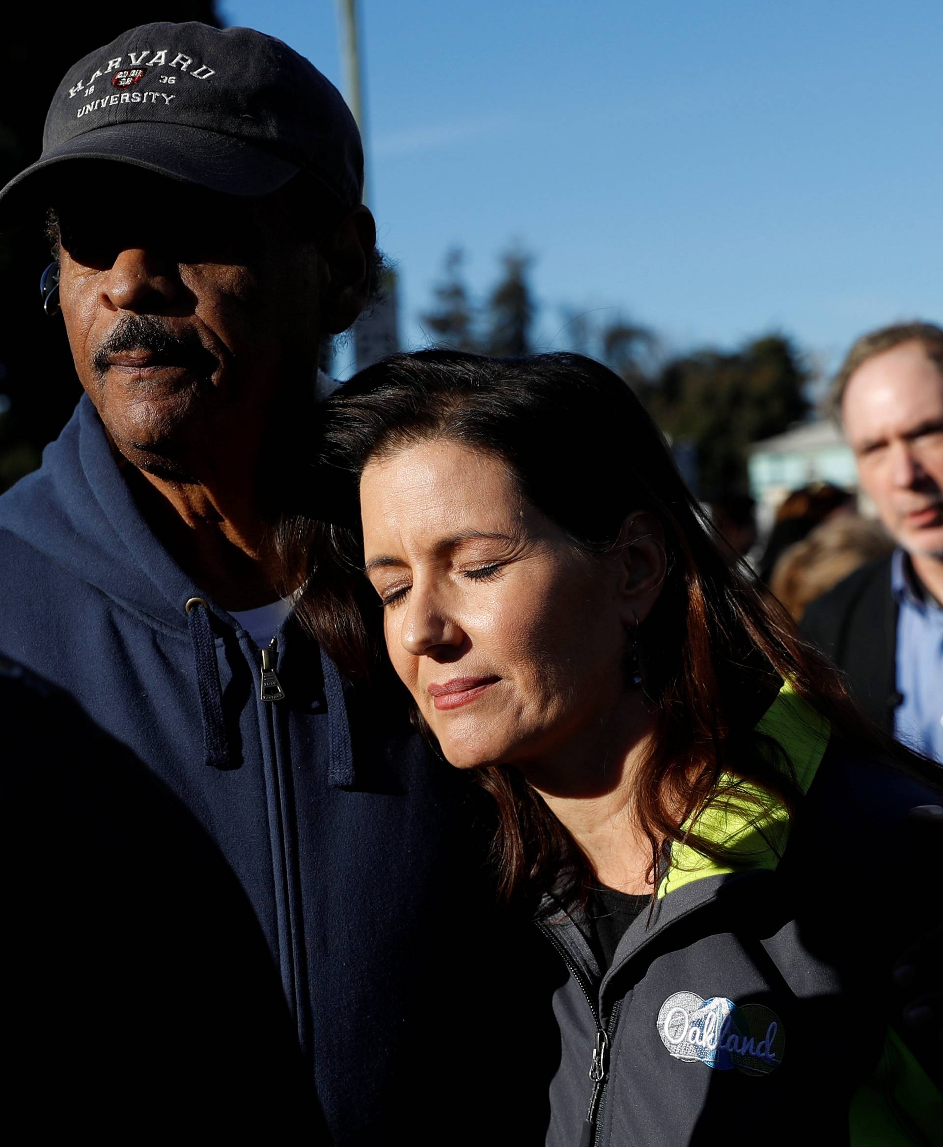 Oakland City Council Member Larry Reid (L) embraces Mayor Libby Schaaf after a new conference at the scene of a fire in the Fruitvale district of Oakland