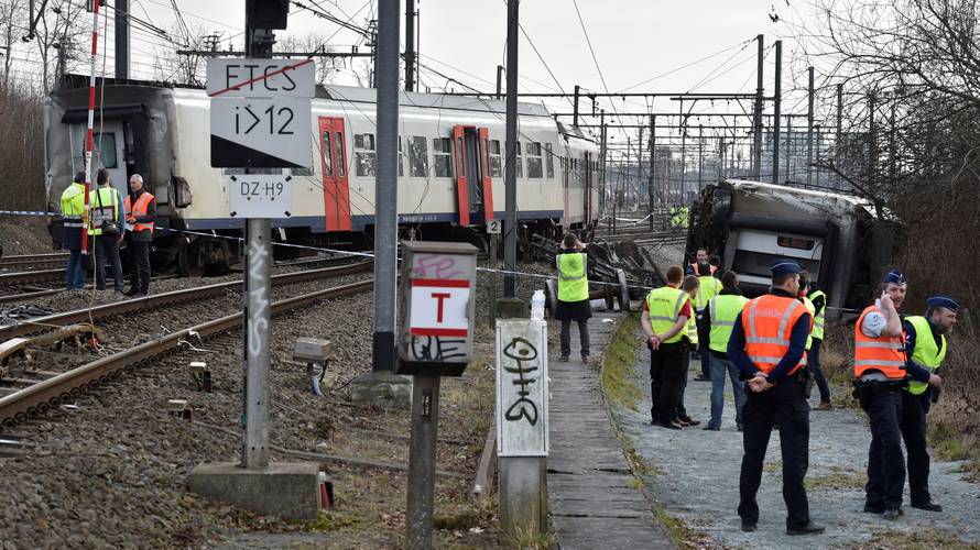 Rescuers and police officers stand next to the wreckage of a passenger train after it derailed in Kessel-Lo near Leuven