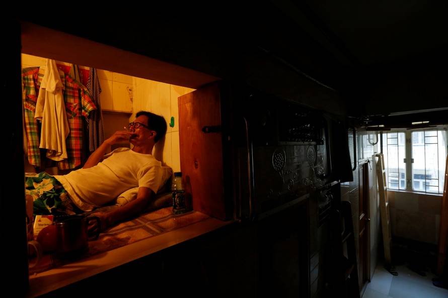 Unemployed Hong Kong resident Simon Wong, 61, smokes inside his 4-by-6-feet partitioned unit, or "coffin unit", with a monthly rent of HK$1,750 ($226) in Hong Kong