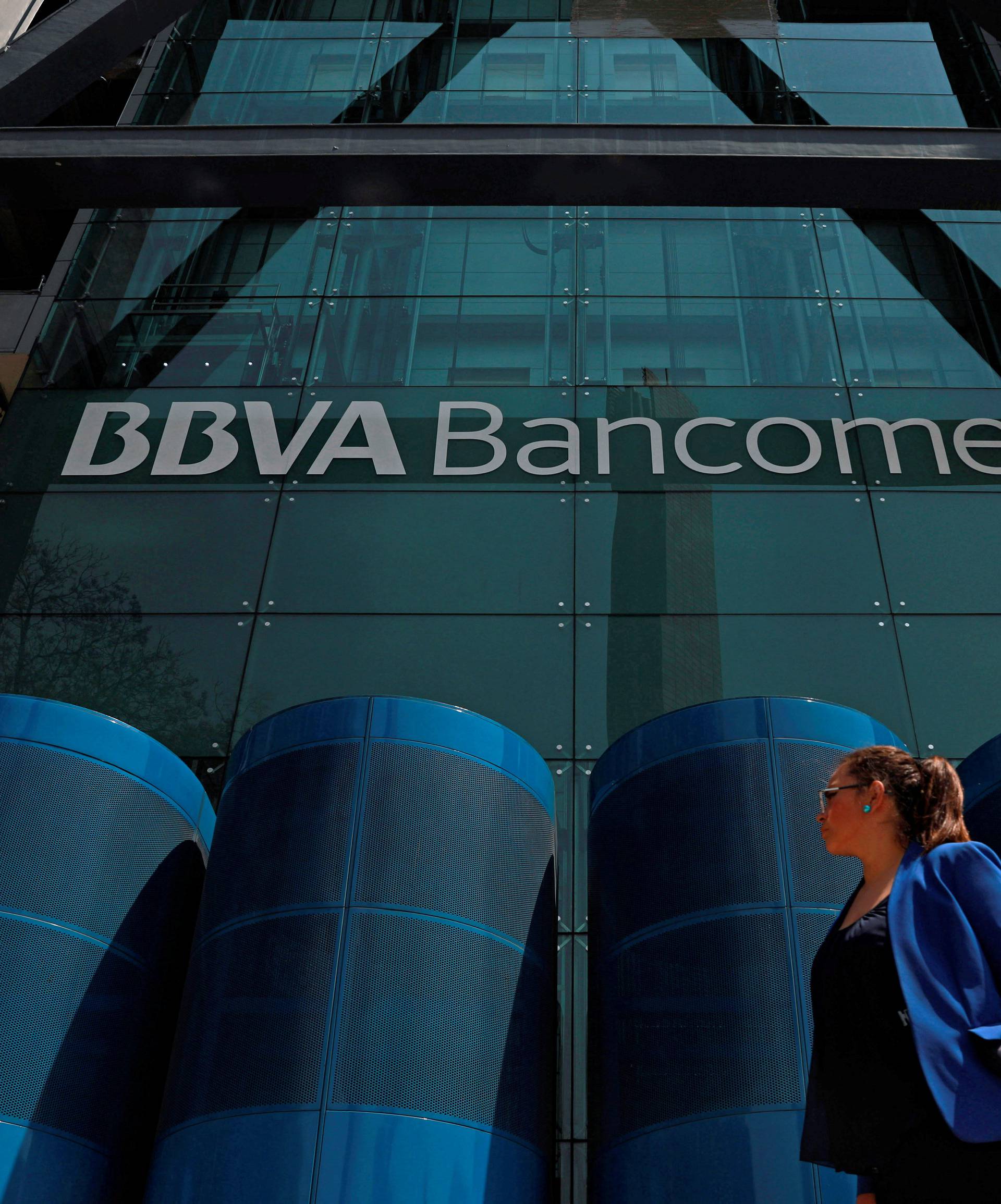 A woman walks past the BBVA building after people were evacuated, in Mexico City
