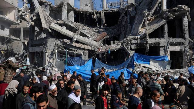 FILE PHOTO: Palestinians shop near the ruins of houses and buildings destroyed in Israeli strikes during the conflict