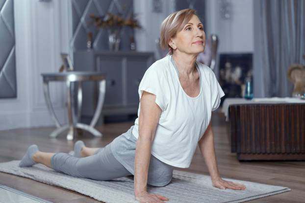 Mature woman stands in upward-facing dog pose