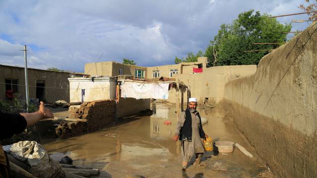 An Afghan man cleans up his damaged home after the heavy flood in the Khushi district of Logar
