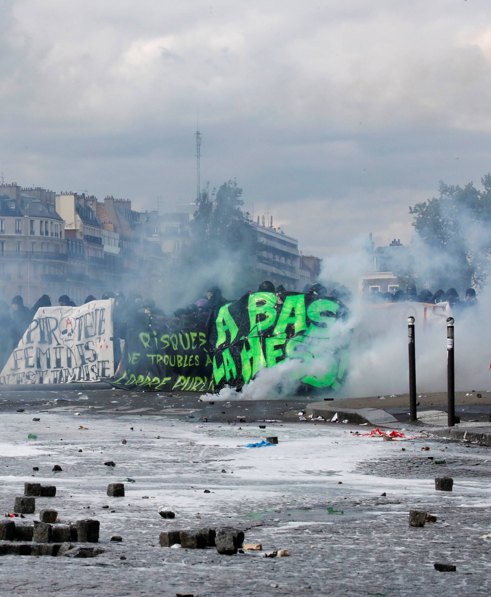 Paving stones are scattered on the street as tear gas fills the air during clashes at the May Day labour union rally in Paris