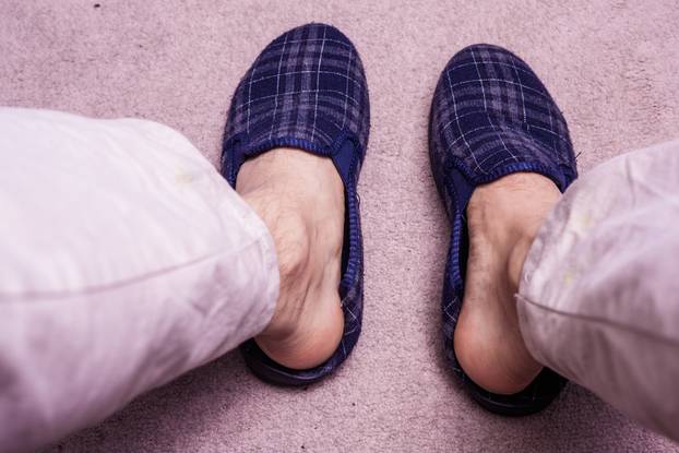 Feet wearing slippers on carpet