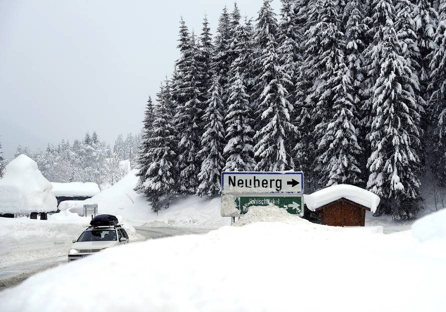 A car is seen on a road during heavy snowfall in Filzmoos