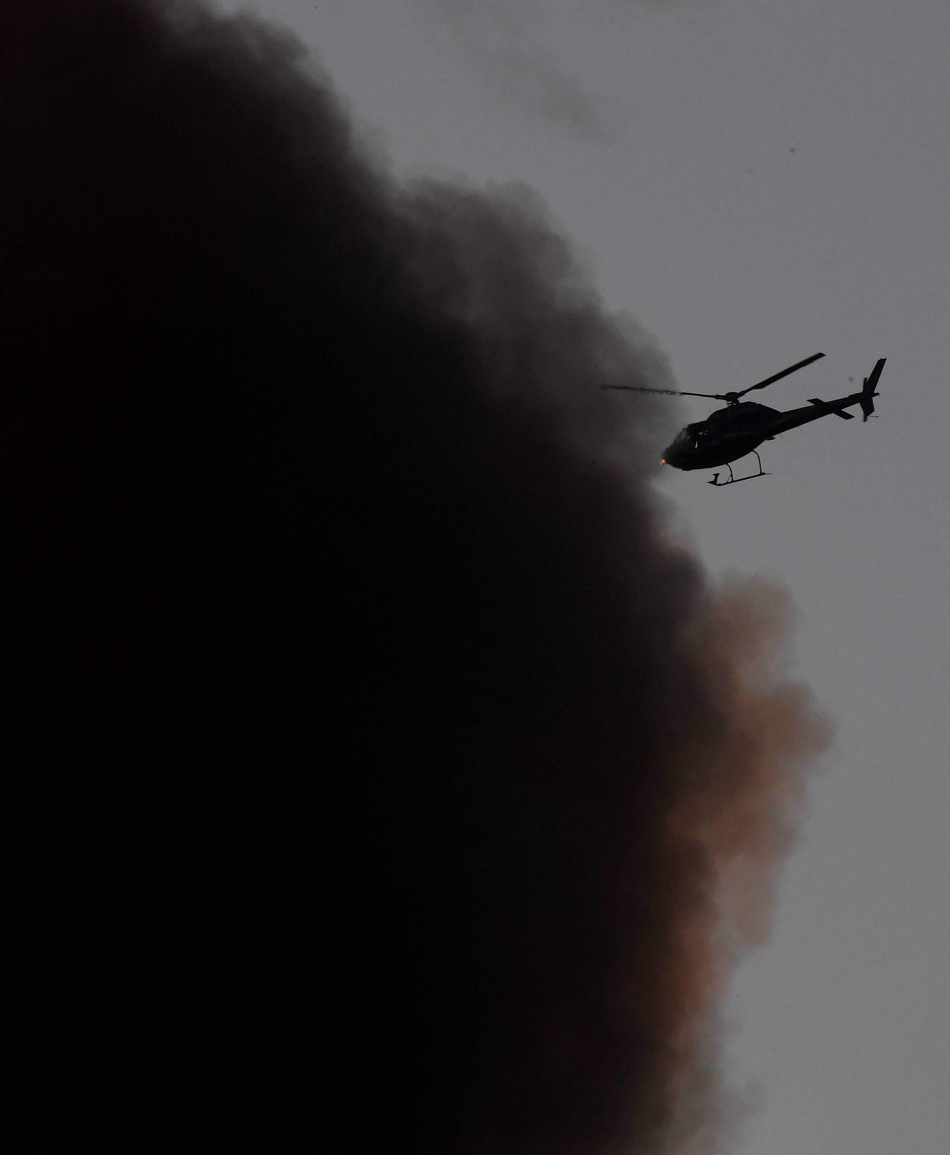 A helicopter is seen as smoke billows from a serious fire in a tower block at Latimer Road in West London