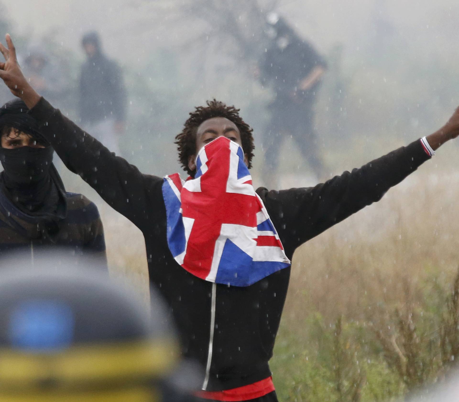 A migrant reacts near French riot police during a protest near the area called the "jungle" where they live in Calais