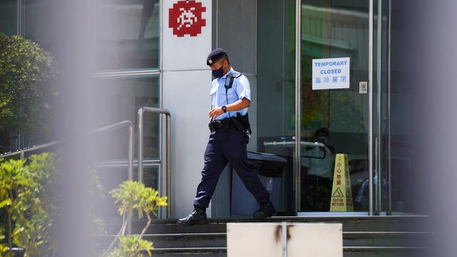 A police officer walks outside the headquarters of Apple Daily and Next Media after police arrested five Apple Daily executives were suspected to have breached the new national security law, in Hong Kong