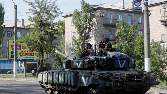 Service members of pro-Russian troops ride a tank in Popasna