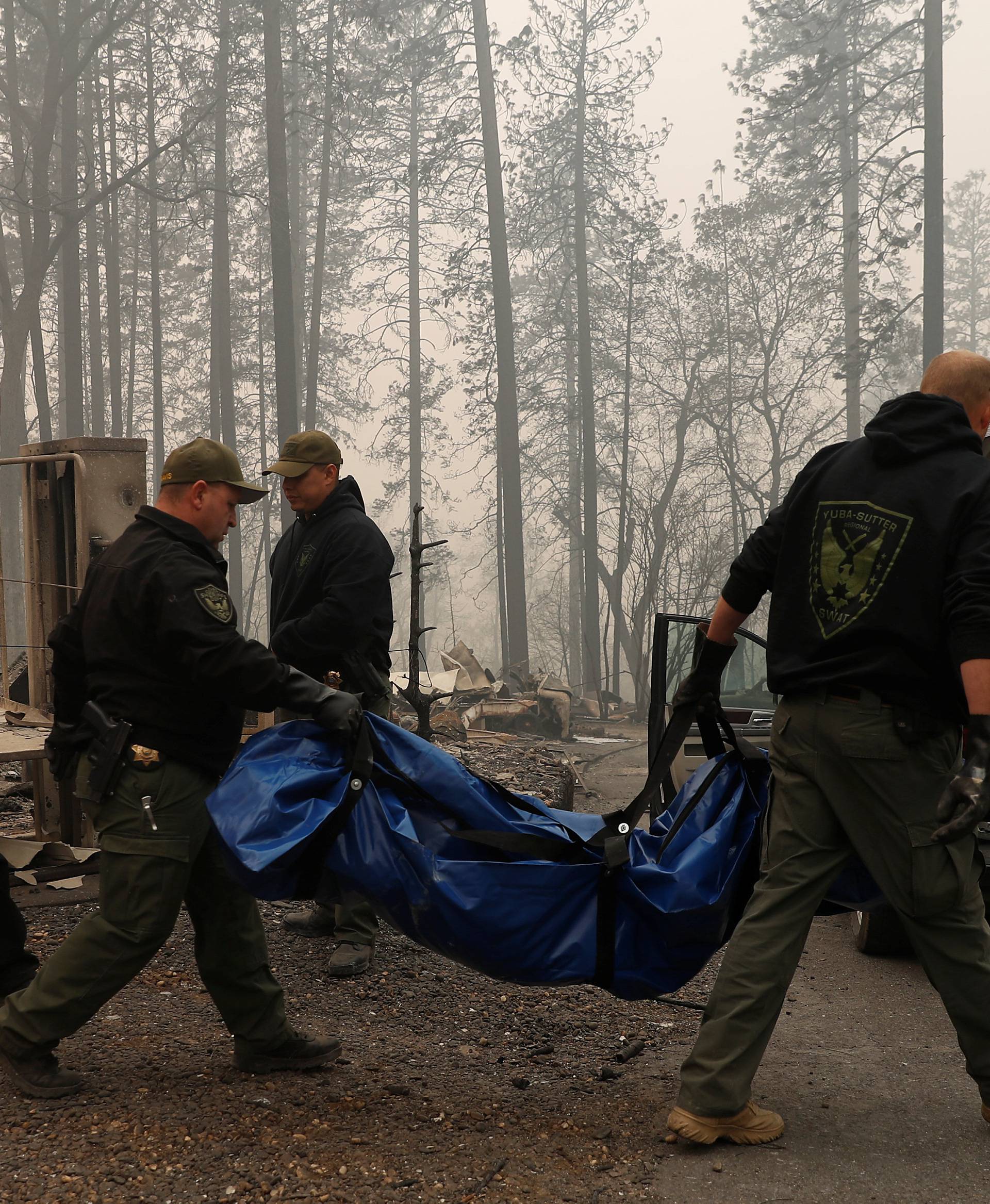 Yuba and Butte County Sheriff deputies carry a body bag with a deceased victim during the Camp fire in Paradise