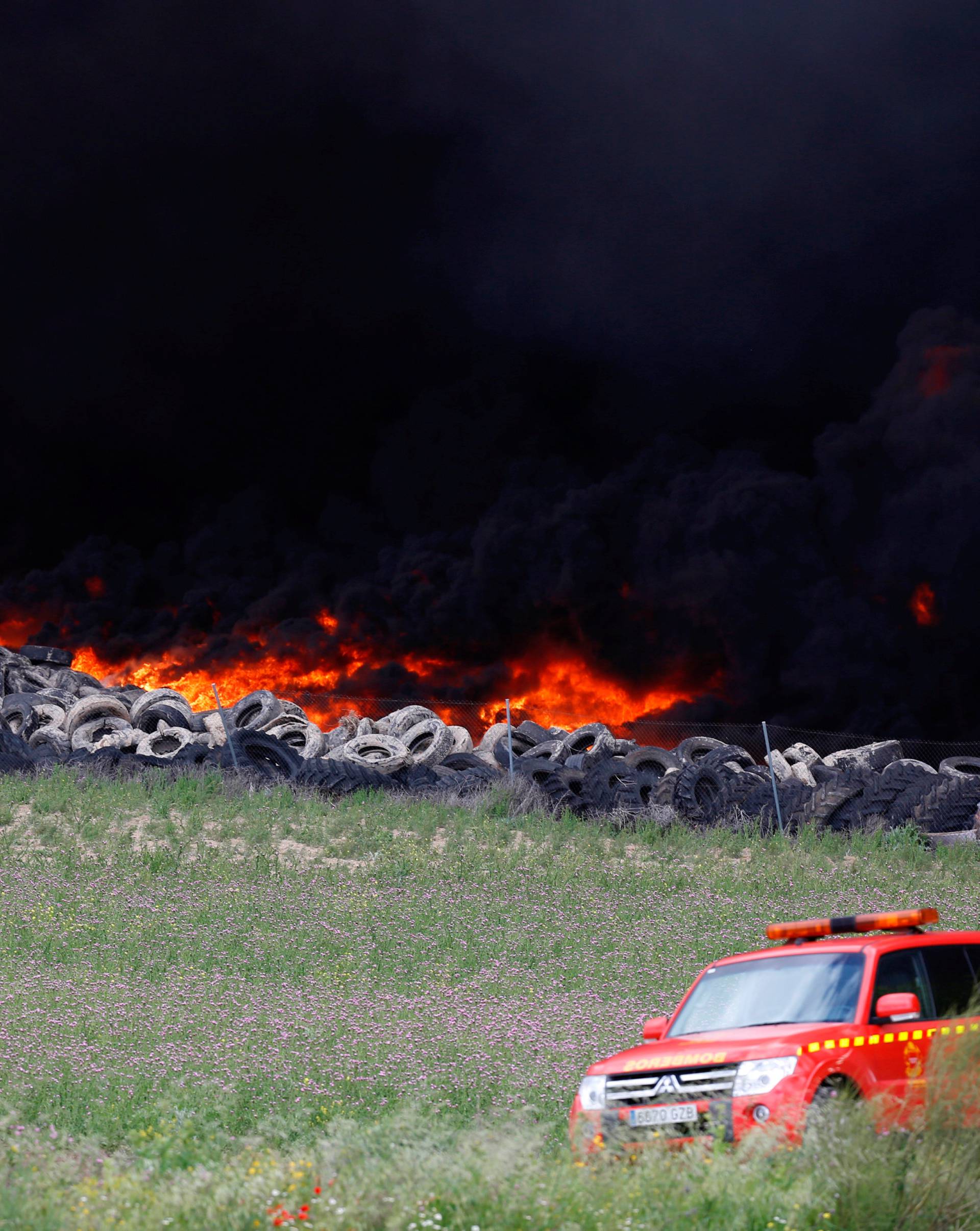 An emergency car stands near a fire at a tire dump near a residential development in Sesena