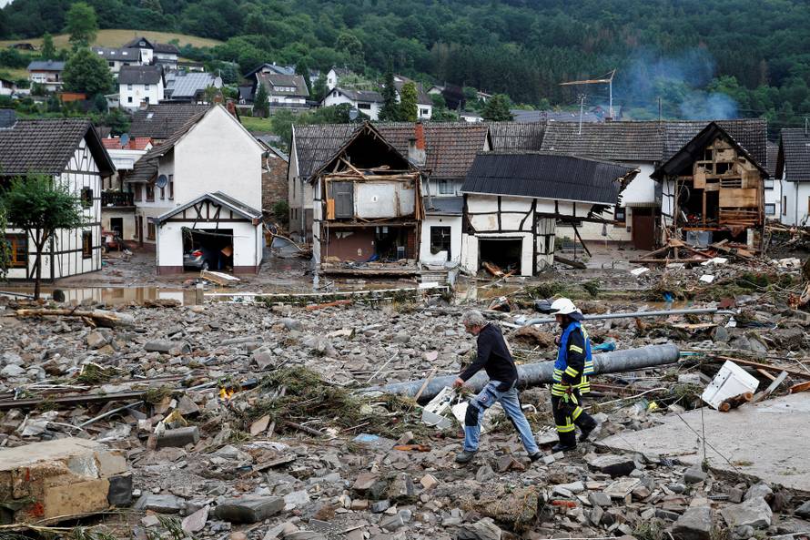 A man and firefighter walk through debris in Schuld