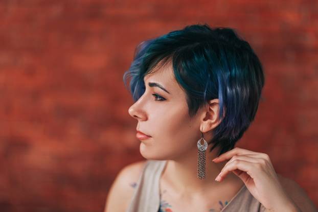 Beautiful young woman with stylish green and purple hair and tattoo on her body
