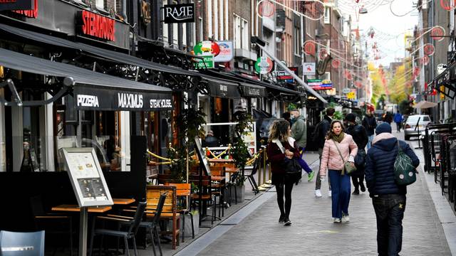 FILE PHOTO: People walk past restaurants and bars in Amsterdam.