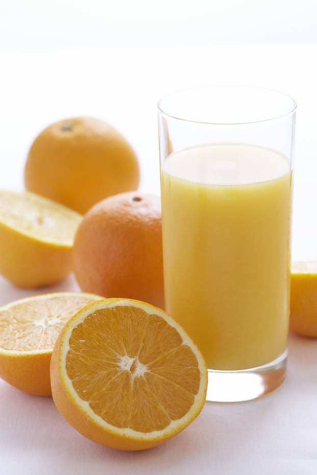 Oranges by orange juice in glass, close-up