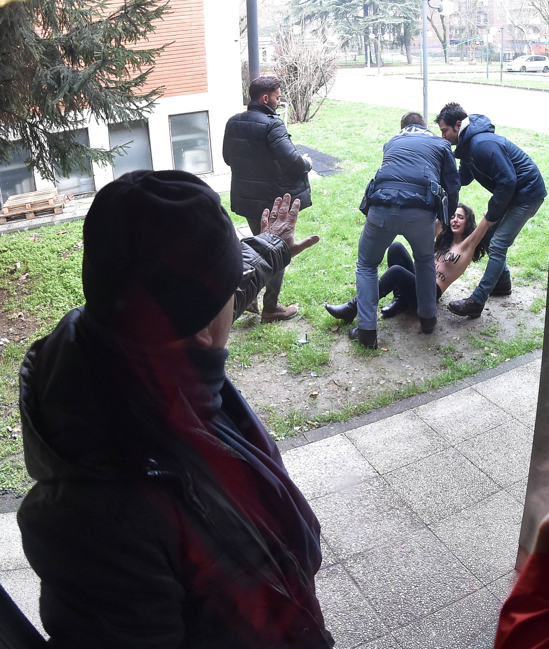 Italian policemen block an activist of women's rights group Femen in the polling station where Forza Italia party leader Silvio Berlusconi casted his vote in Milan