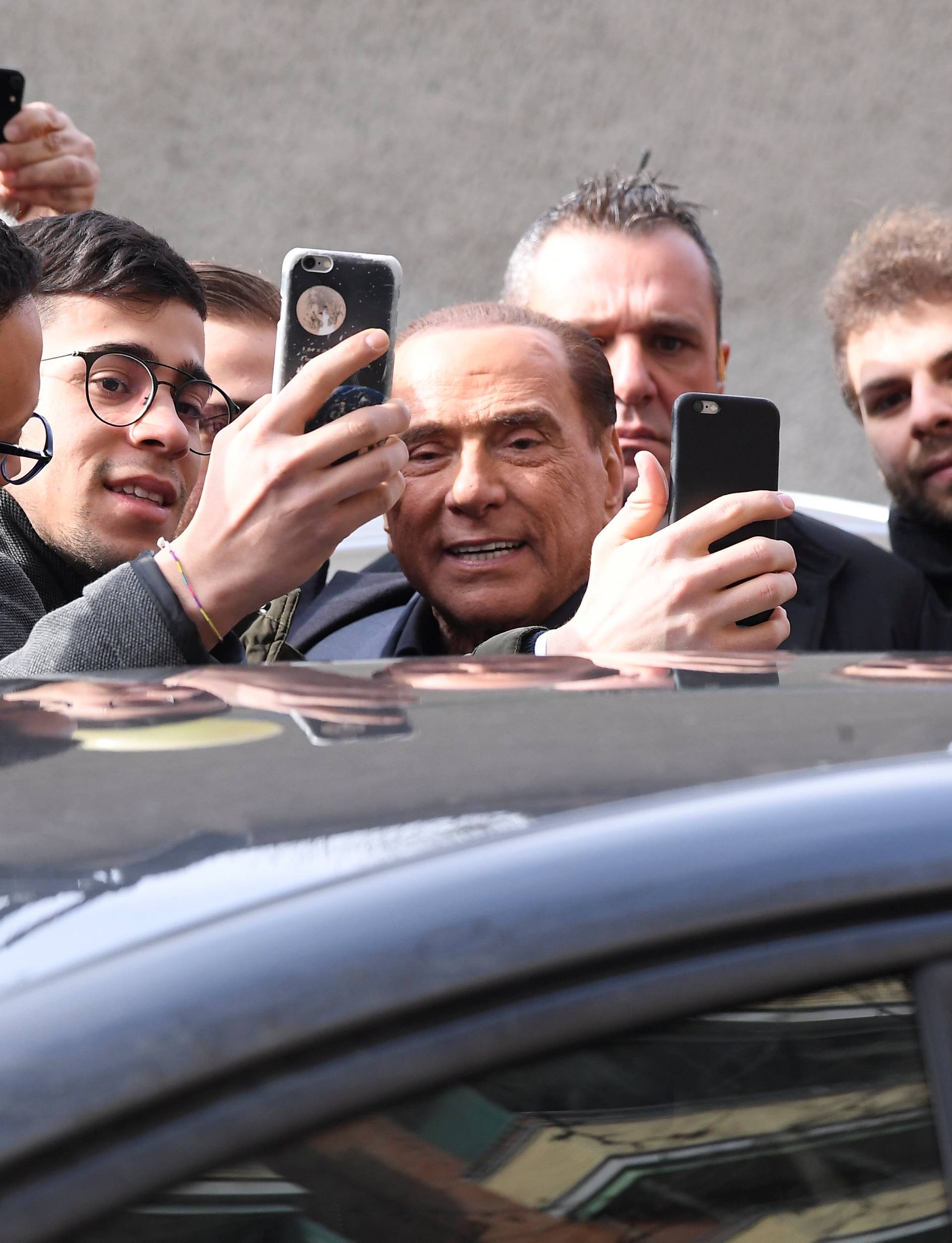 Forza Italia party leader Silvio Berlusconi poses for a selfie after casting his vote at a polling station in Milan