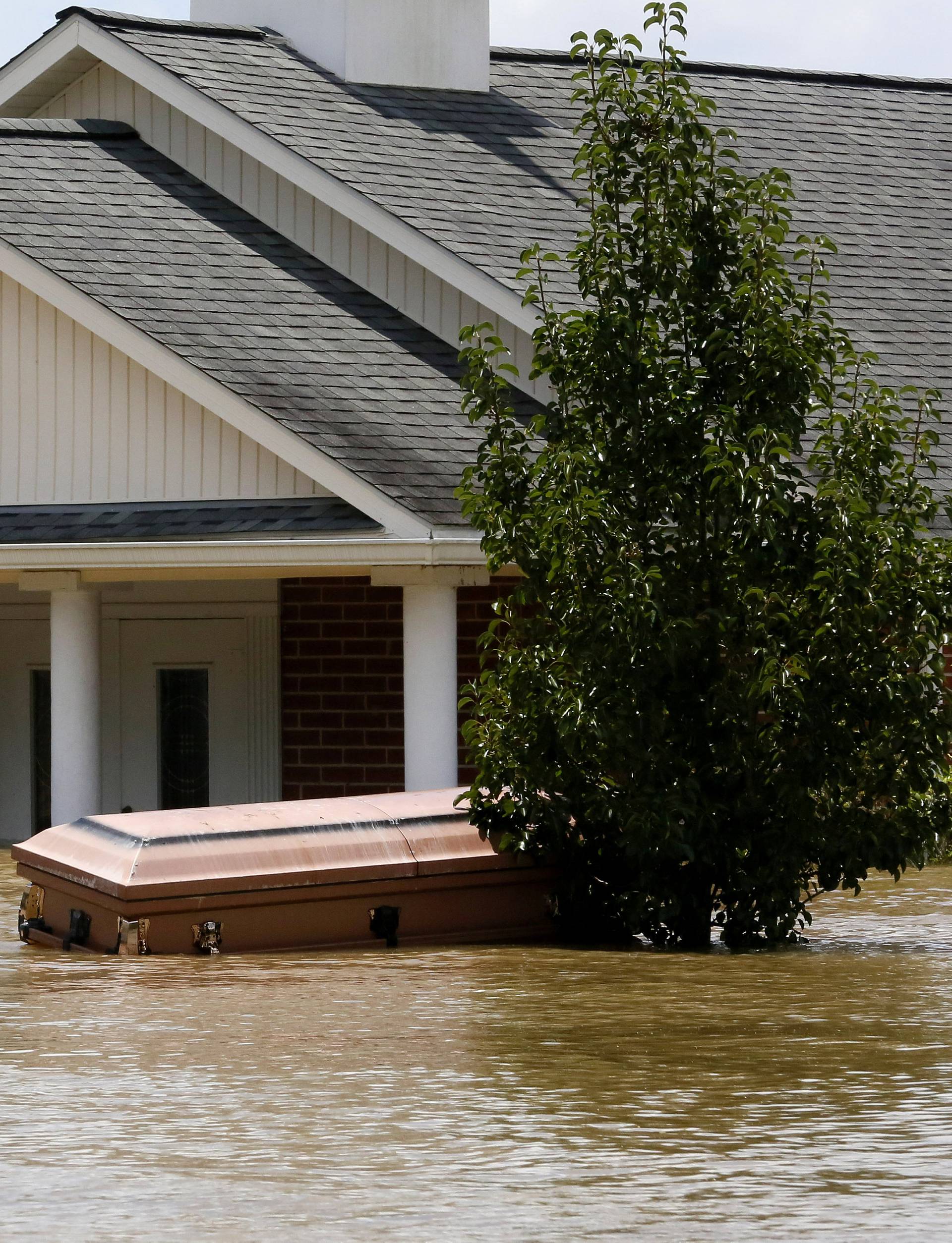 A casket is seen in front of a partially submerged church in Ascension Parish