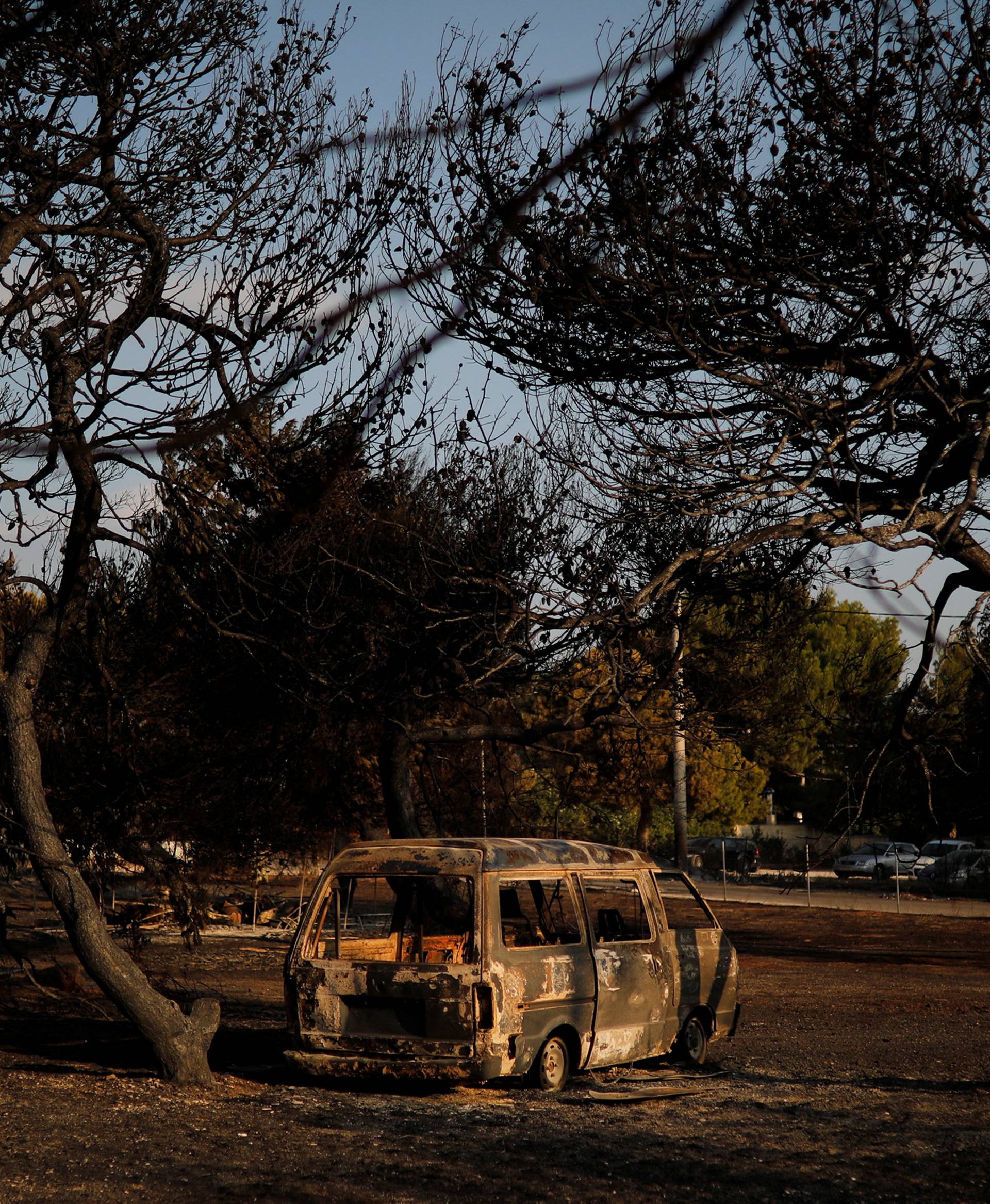 A member of a rescue team searches inside a destroyed building following a wildfire at the village of Mati