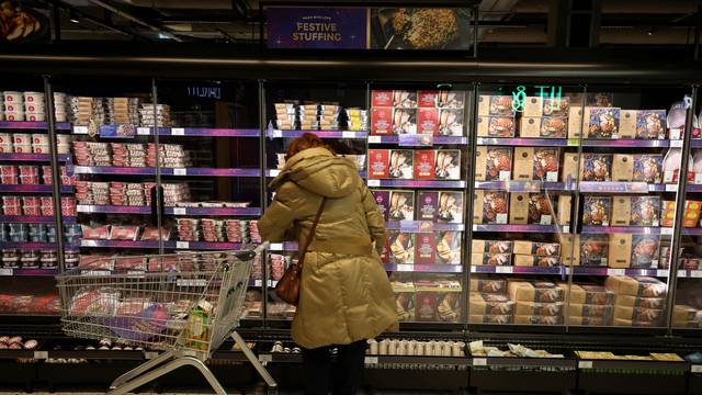 A customer looks at a display of Christmas meats and turkeys in the food hall at the M&S store inside the Trafford Centre in Manchester