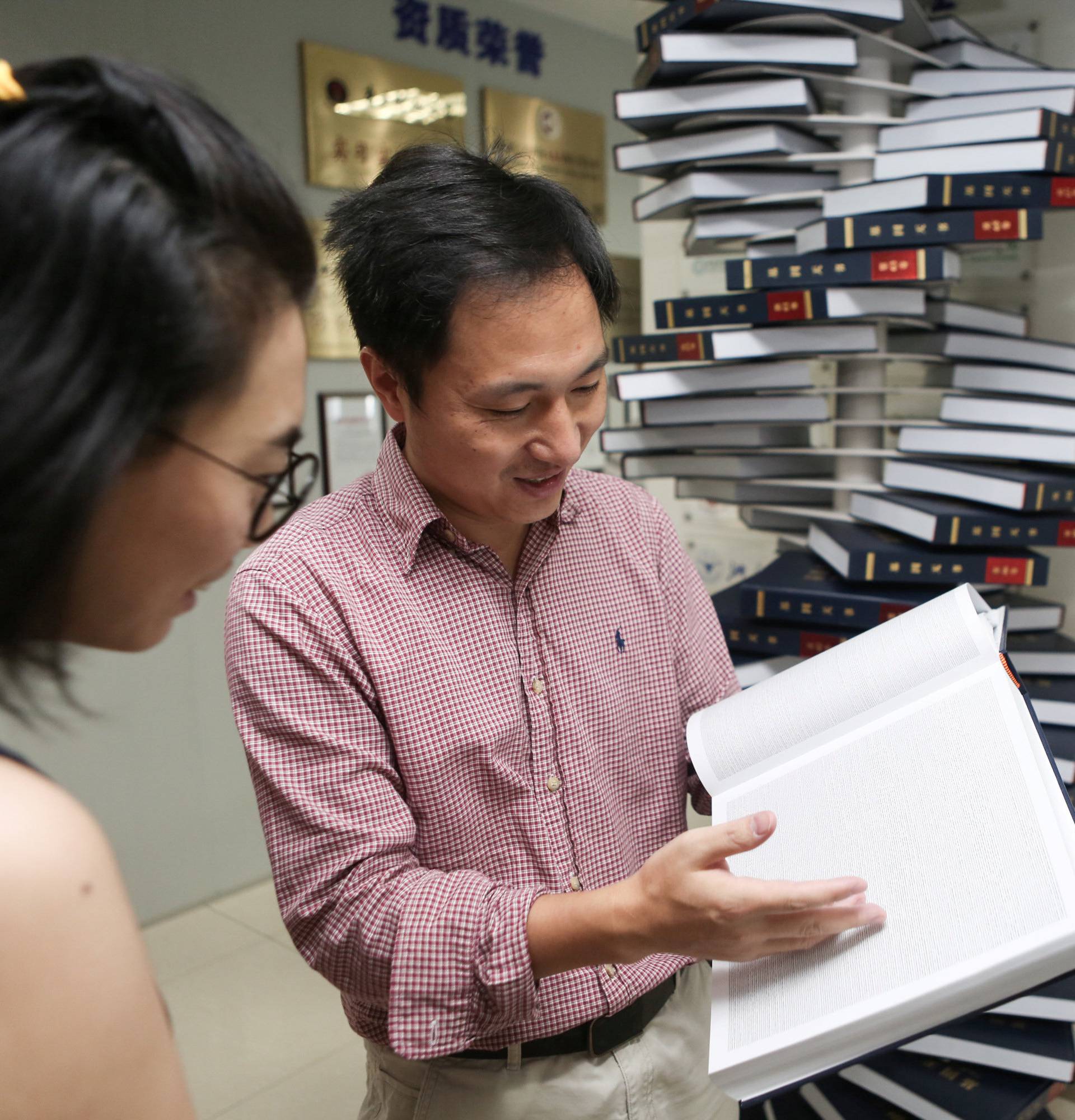 Scientist He Jiankui shows "The Human Genome", a book he edited, at his company Direct Genomics in Shenzhen