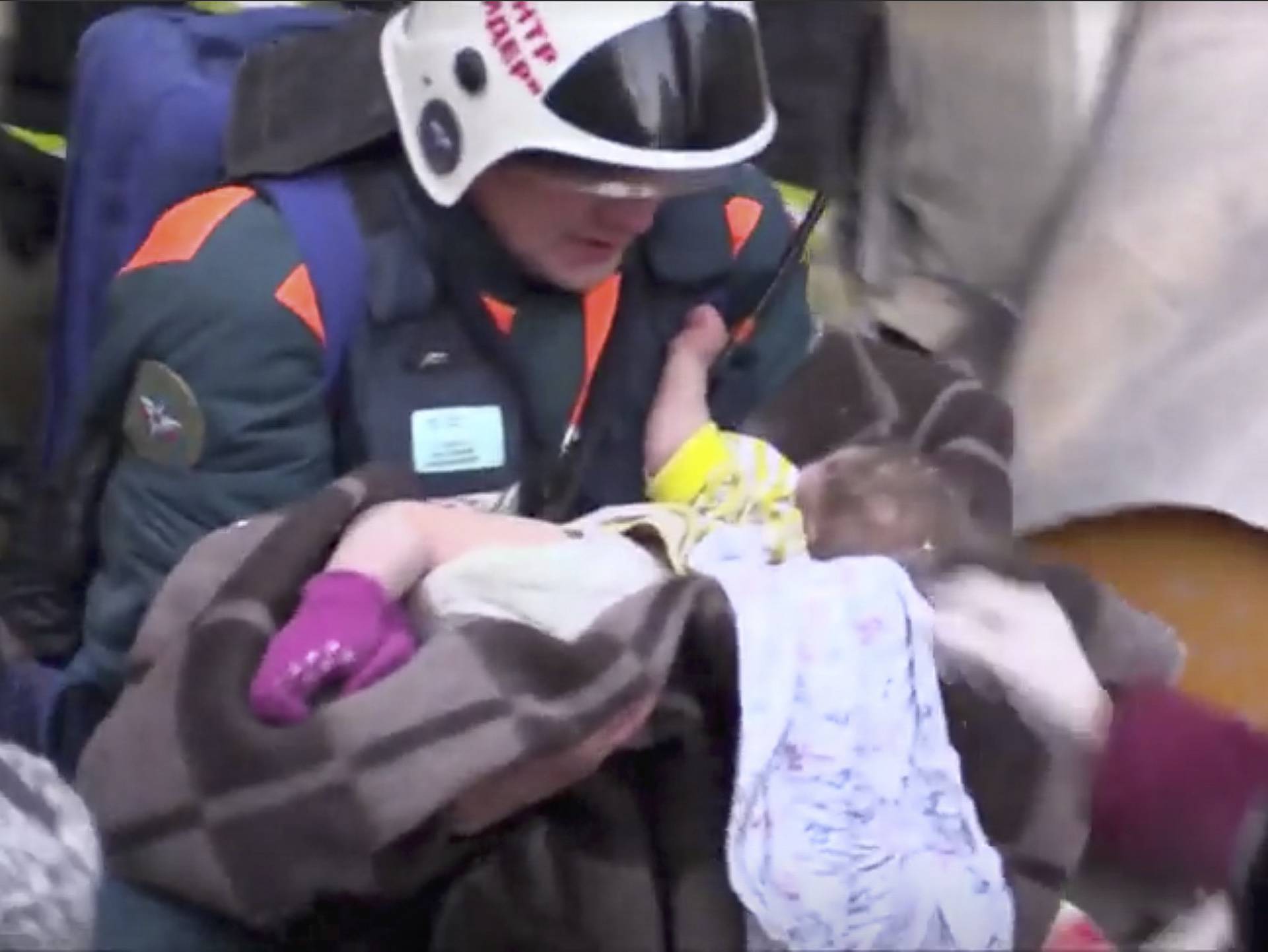 A still image taken from a video footage showsaA rescuer carries a 10-month-old child found alive in the rubble of a Russian apartment block that partially collapsed after a suspected gas blast in Magnitogorsk