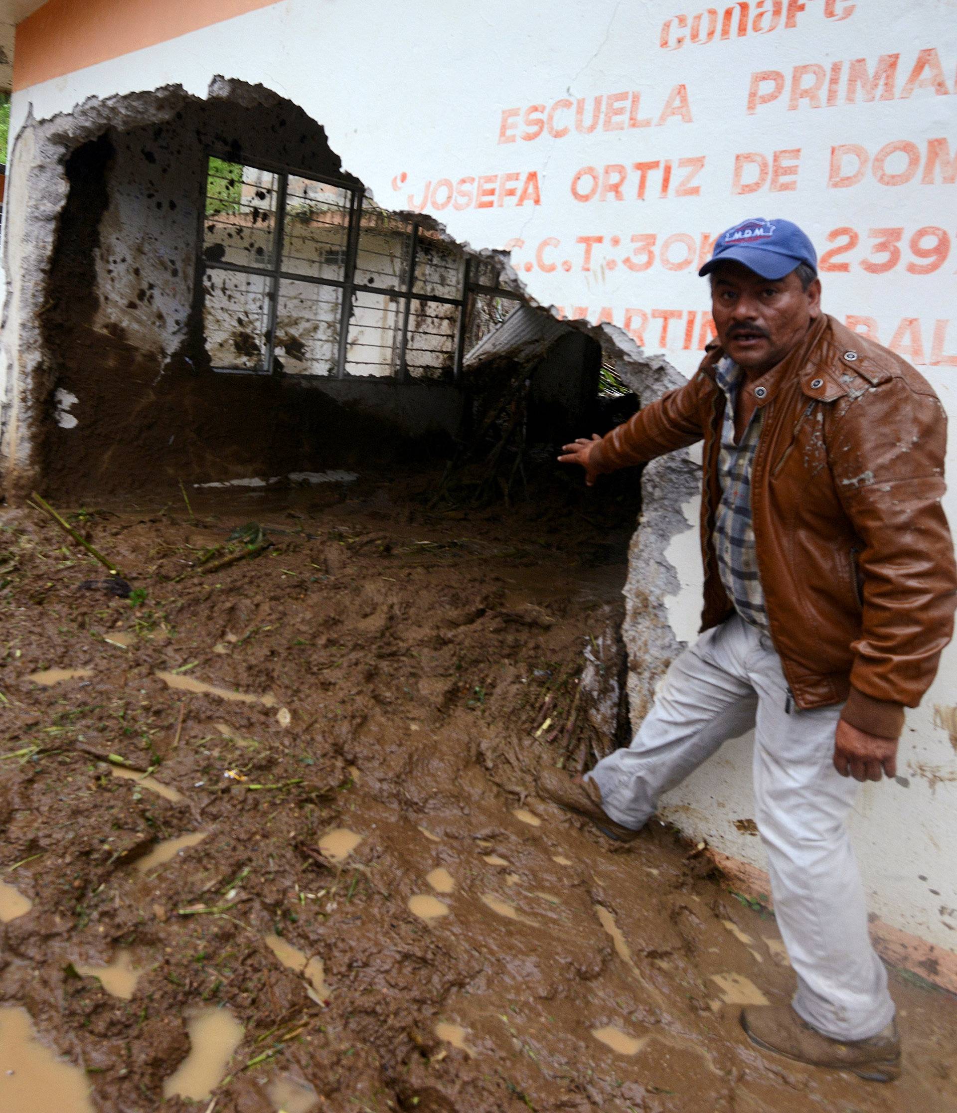 Resident shows a classroom damaged by a mudslide following heavy showers caused by the passing of Tropical Storm Earl, in the town of Temazolapa